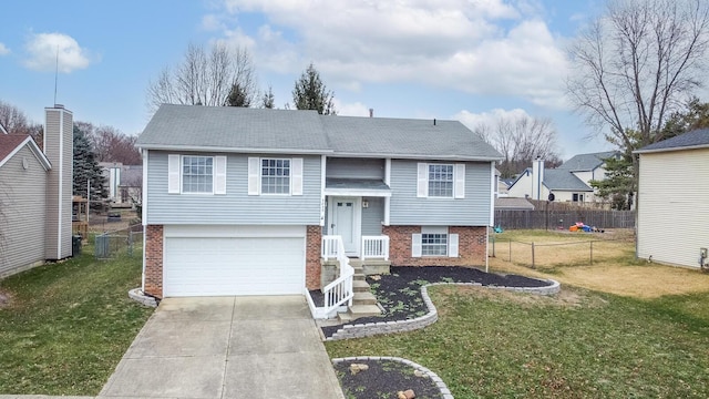 split foyer home with fence, an attached garage, concrete driveway, a front lawn, and brick siding