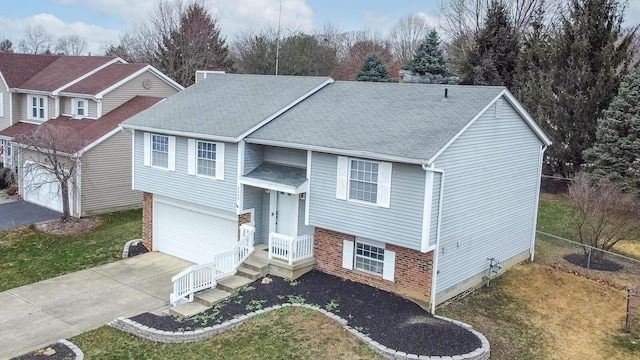 bi-level home with fence, brick siding, driveway, and a shingled roof