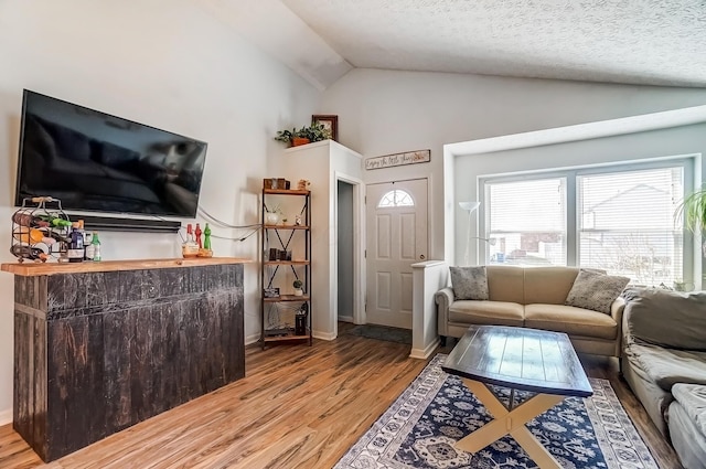 living area with vaulted ceiling, light wood-style flooring, and a textured ceiling