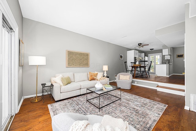 living area featuring a ceiling fan, baseboards, and wood finished floors