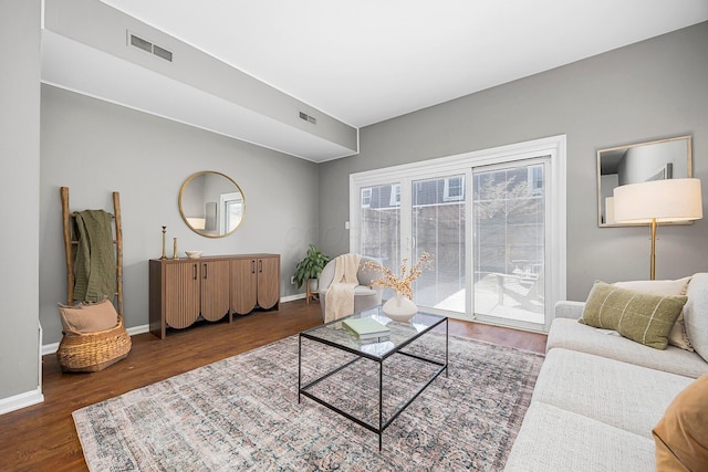 living area with visible vents, baseboards, and wood finished floors