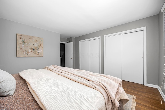 bedroom featuring two closets and dark wood-style floors