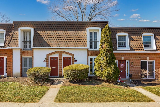 townhome / multi-family property with mansard roof and brick siding