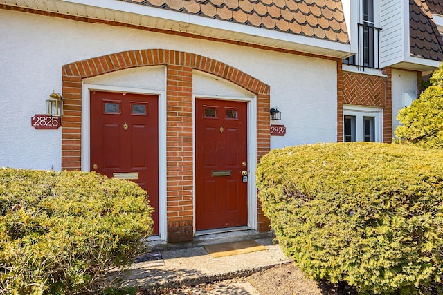 doorway to property with mansard roof and stucco siding