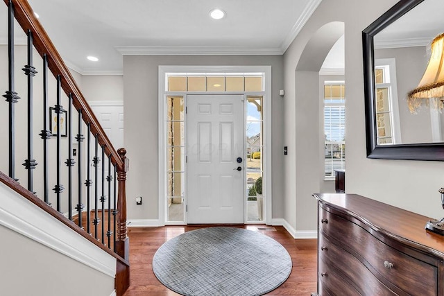 entryway featuring dark wood finished floors, stairway, arched walkways, crown molding, and baseboards