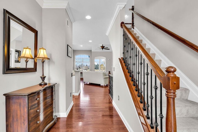 stairs featuring recessed lighting, wood finished floors, baseboards, and ornamental molding