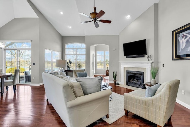 living room featuring dark wood finished floors, a fireplace with flush hearth, high vaulted ceiling, and baseboards