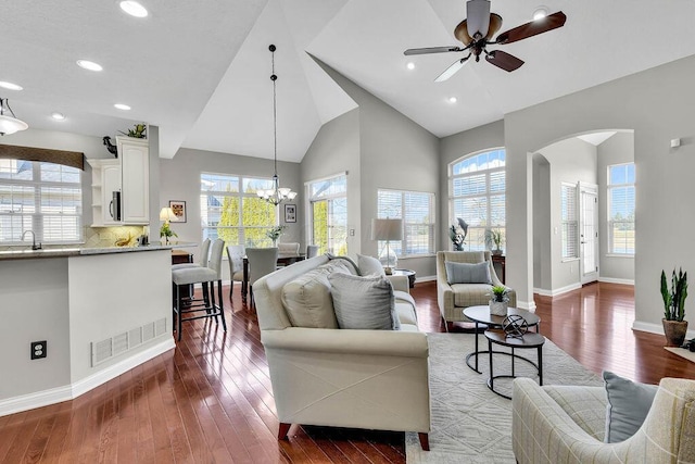 living room featuring hardwood / wood-style flooring, baseboards, arched walkways, and visible vents