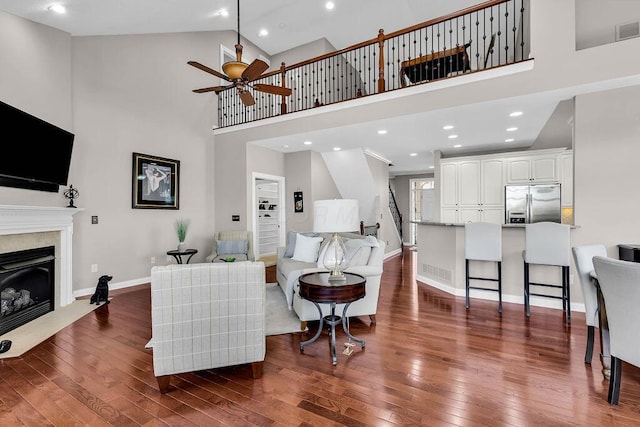 living room featuring a ceiling fan, baseboards, high vaulted ceiling, dark wood-style flooring, and a high end fireplace