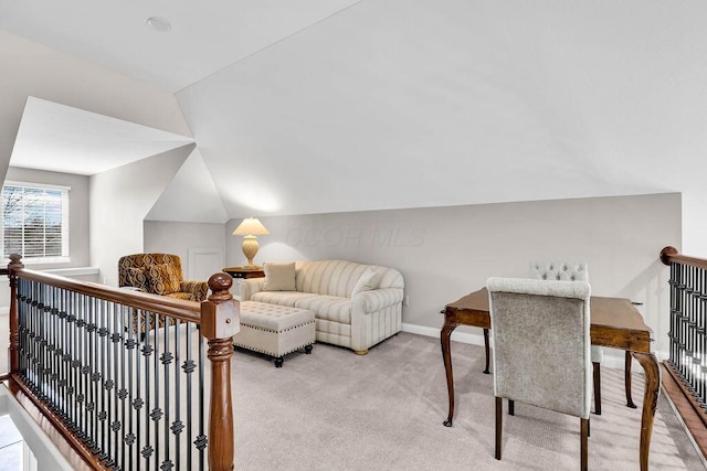 living area with baseboards, lofted ceiling, and light colored carpet