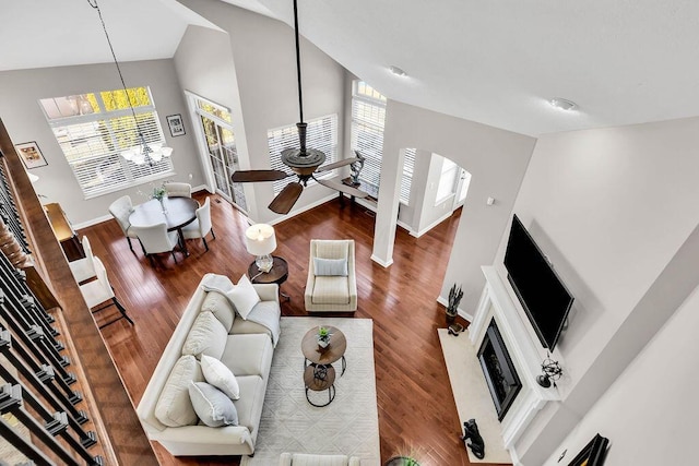 living room with high vaulted ceiling, a ceiling fan, wood finished floors, arched walkways, and baseboards