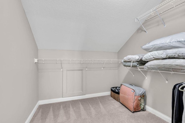 walk in closet with vaulted ceiling and carpet flooring