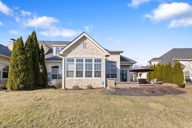 back of property featuring a yard and stone siding