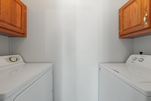 clothes washing area with washing machine and clothes dryer and cabinet space