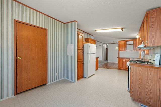 kitchen with range with gas cooktop, light floors, freestanding refrigerator, and wallpapered walls