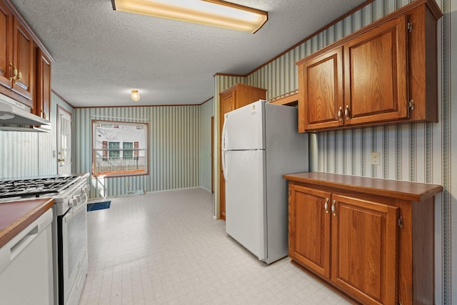 kitchen featuring brown cabinets, white appliances, wallpapered walls, and a textured ceiling