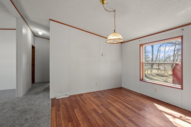 spare room featuring visible vents, a textured ceiling, wood finished floors, and ornamental molding