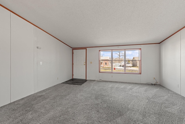 carpeted empty room with vaulted ceiling, a textured ceiling, and ornamental molding