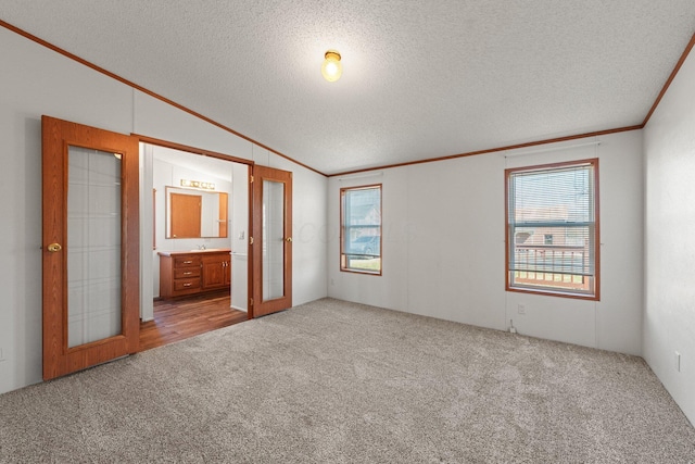 unfurnished bedroom with carpet floors, lofted ceiling, french doors, a textured ceiling, and crown molding