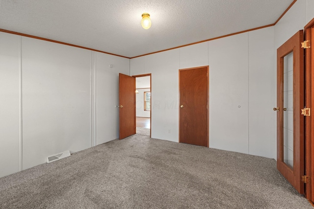 spare room featuring visible vents, carpet floors, a textured ceiling, and ornamental molding