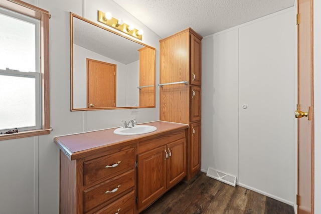 bathroom with visible vents, a textured ceiling, wood finished floors, lofted ceiling, and vanity