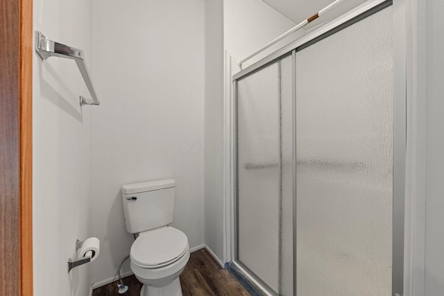 bathroom with baseboards, wood finished floors, toilet, and a stall shower