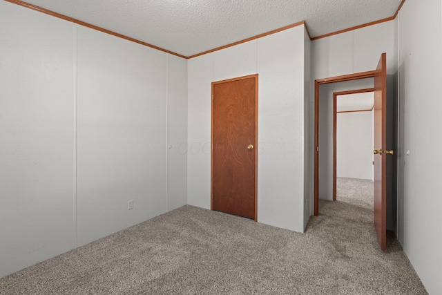 unfurnished room with a textured ceiling, carpet flooring, and crown molding