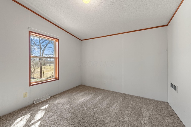 carpeted spare room featuring visible vents, a textured ceiling, ornamental molding, and vaulted ceiling