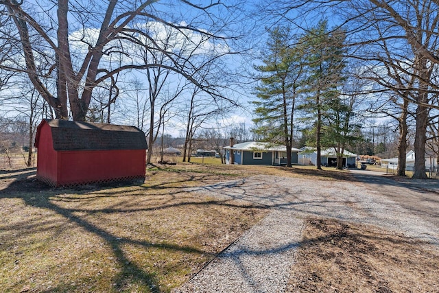 view of yard featuring driveway, a storage unit, and an outdoor structure