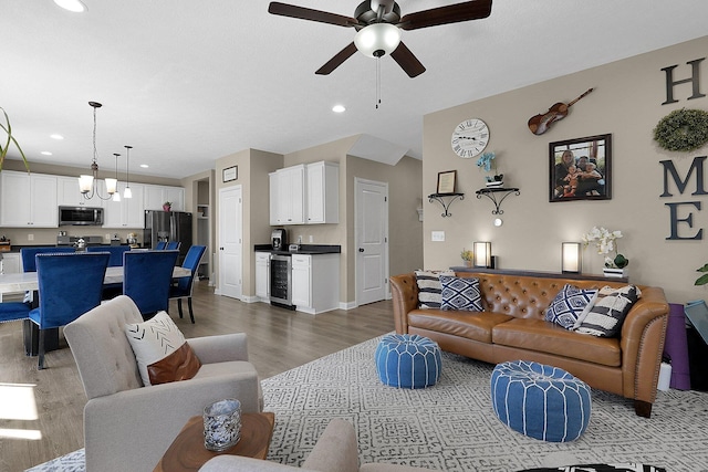 living area with wine cooler, recessed lighting, ceiling fan with notable chandelier, and wood finished floors