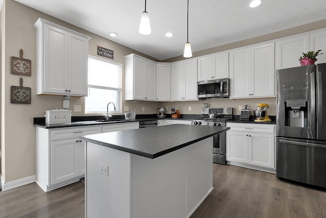 kitchen with dark countertops, white cabinets, appliances with stainless steel finishes, and a sink