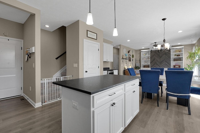 kitchen with white cabinetry, dark countertops, hanging light fixtures, and dark wood-style flooring