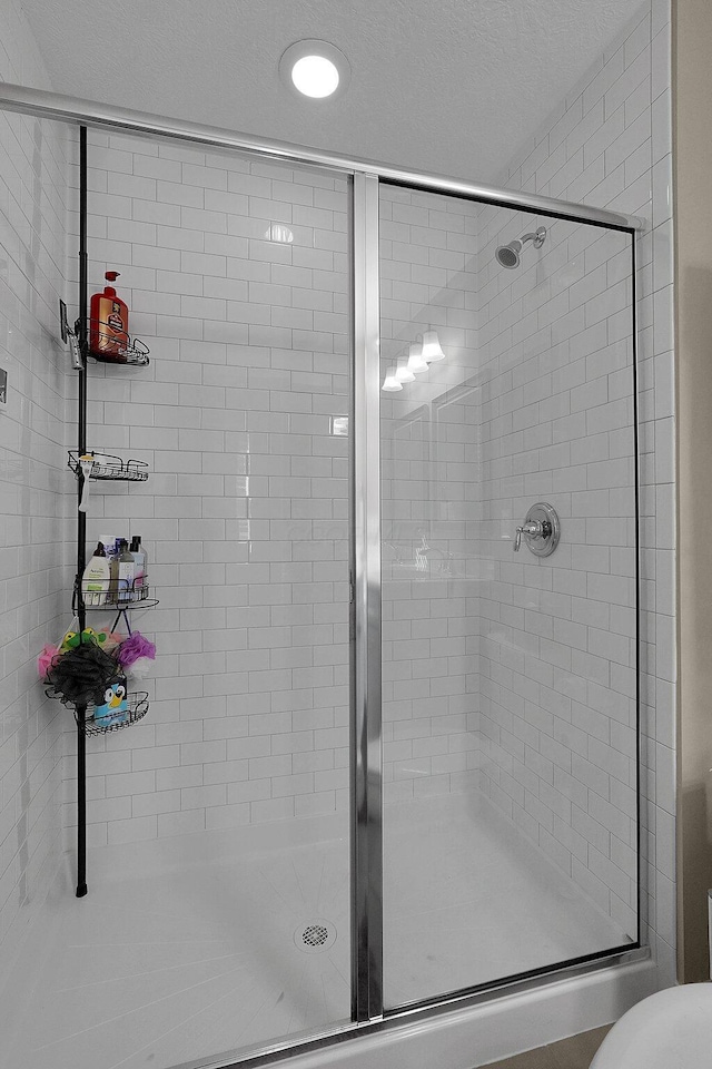 full bathroom with a textured ceiling and a stall shower