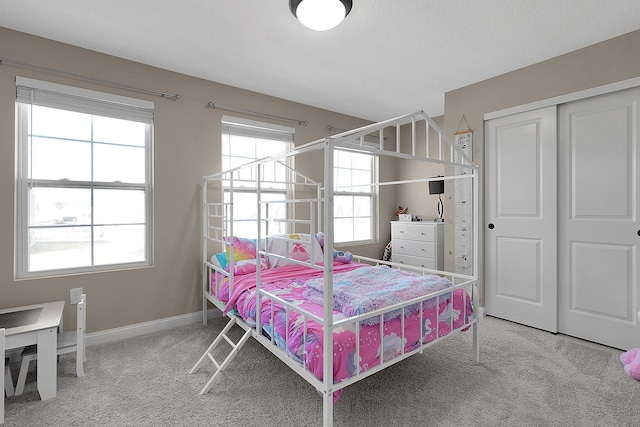 carpeted bedroom featuring a closet, multiple windows, and baseboards