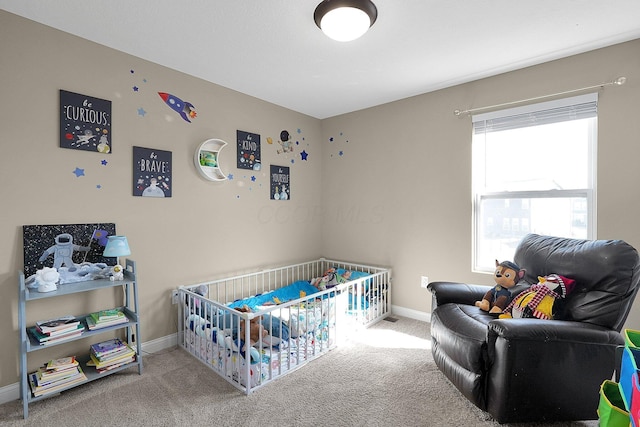 bedroom with baseboards, a nursery area, and carpet flooring