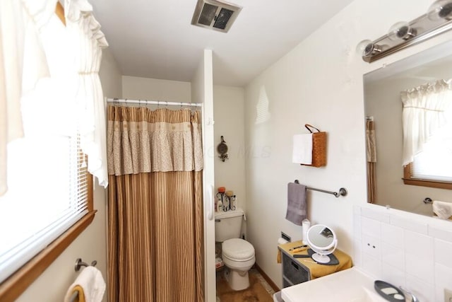 bathroom featuring a shower with shower curtain, visible vents, and toilet