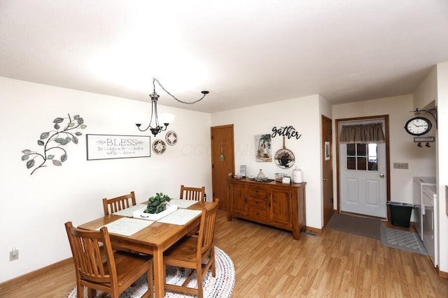 dining area with light wood-style flooring, an inviting chandelier, and baseboards