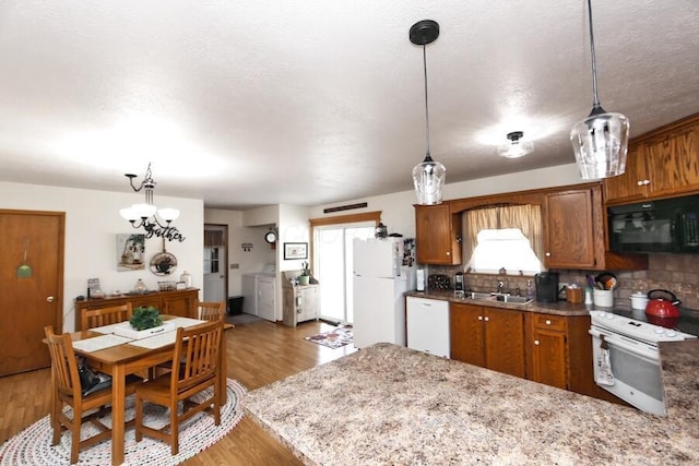 kitchen with a sink, washing machine and dryer, white appliances, light wood-style floors, and brown cabinetry