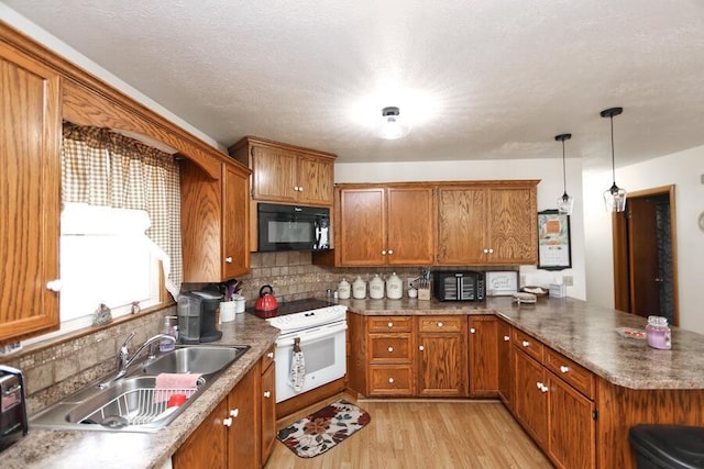 kitchen with brown cabinets, white range with electric cooktop, a sink, light wood-style floors, and black microwave