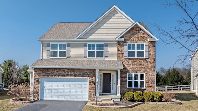 view of front facade featuring a shingled roof, fence, aphalt driveway, stone siding, and an attached garage