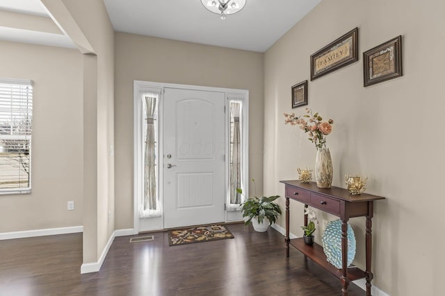 foyer entrance featuring wood finished floors, visible vents, and baseboards