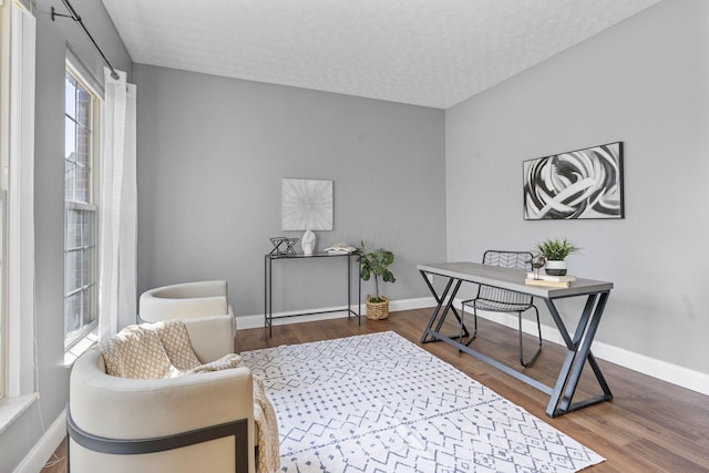 office space featuring baseboards, a textured ceiling, and wood finished floors