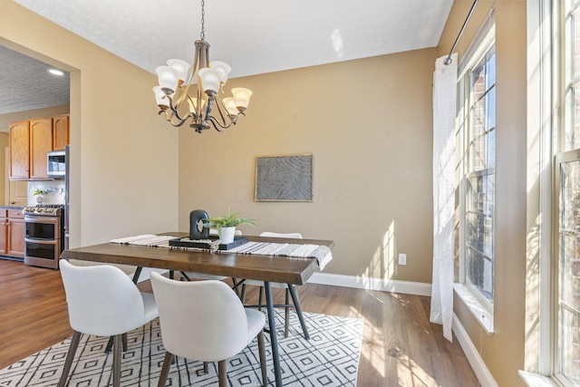 dining area with baseboards, an inviting chandelier, and dark wood-style floors