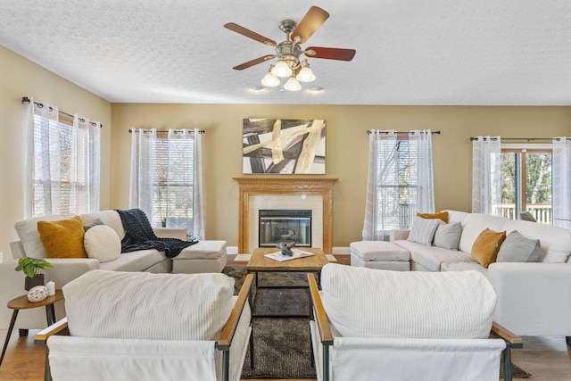 living room with a glass covered fireplace, a textured ceiling, a healthy amount of sunlight, and ceiling fan