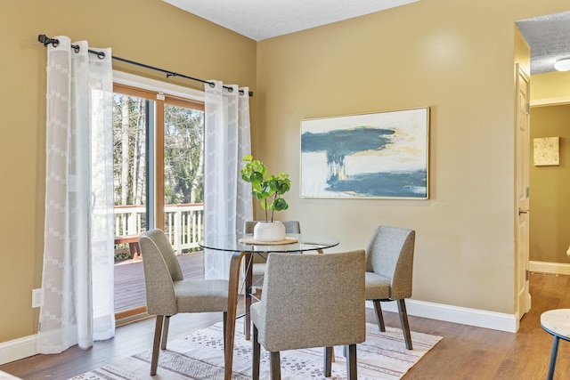 dining space with baseboards and wood finished floors