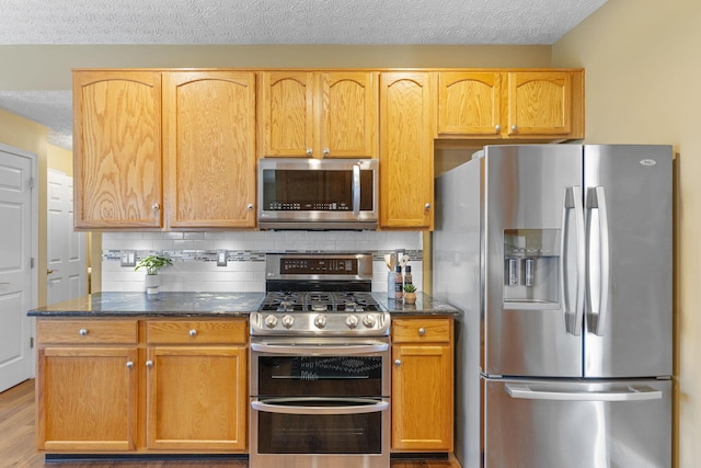 kitchen with dark stone counters, tasteful backsplash, and stainless steel appliances