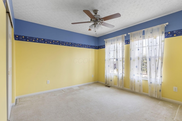 empty room featuring visible vents, a textured ceiling, carpet flooring, baseboards, and ceiling fan