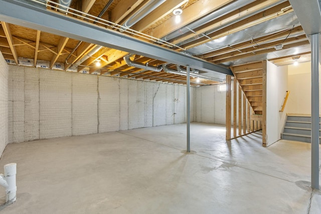 basement featuring stairway and brick wall