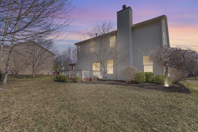 back of house featuring a yard, a deck, and a chimney