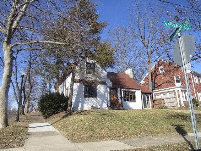 view of front facade featuring a chimney, a front yard, and fence